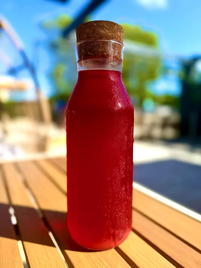 A bottle of homemade berry kompot on an outdoor table