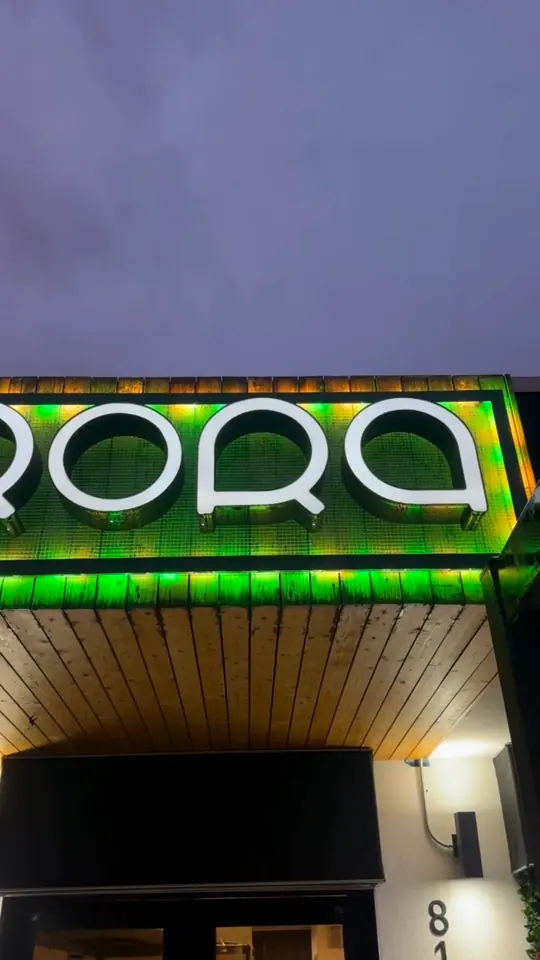 The illuminated Aurora sign above the restaurant entrance at dusk